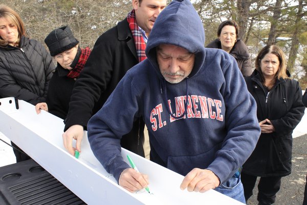 Chairman of the East End Hospice Board of Directors Michael Pitcher signs the final beam that will be used to build the Kanas Center for Hospice Care on Tuesday morning in the parking lot of the East End Hospice office on Old Riverhead Road. KYLE CAMPBELL