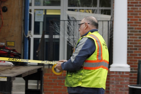 Russ Losse puts caution tape around the library's main entrance. VALERIE GORDON