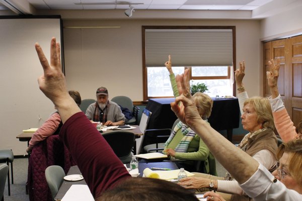 Participants raise their fingers in the air to cast votes for which proposed library improvements should be prioritized if the library board were to float a bond. KYLE CAMPBELL