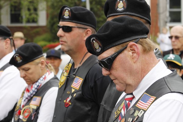The American Legion Hand-Aldrich Post color guard leads a procession down Ponquogue Avenue in Hampton Bays on Monday as pa