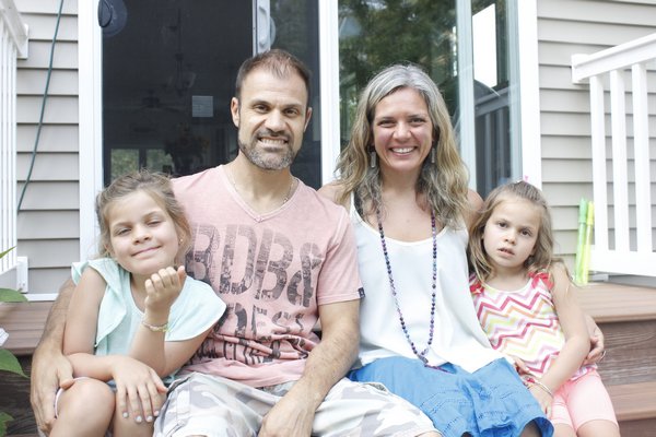 Melissa Mayer and her husband Ken sit on the back porch steps of their Hampton Bays home with their two daughters. VALERIE GORDON 