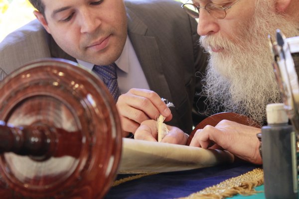  holds her son Benjamin as he grabs the quill of Rabbi Moshe Klein. Rabbi Klein wrote the final letters into a Sefer Torah scroll donated  to the Hampton Synagogue by the Podolsky family on Friday. KYLE CAMPBELL