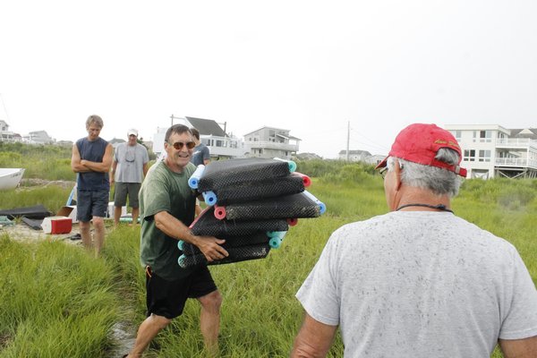  a community aquaculture specialist with the Cornell Cooperative Extension of Suffolk County sets up the rigging for an oyster planting event organized by the Moriches Bay Project on Saturday morning in West Hampton Dunes. KYLE CAMPBELL