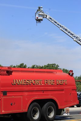 A Westhampton Beach firefighter battles a brush fire Monday morning from a bucket truck on Old Riverhead Road in Westhampton. KYLE CAMPBELL