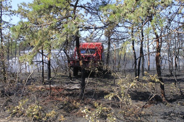 Brush trucks from various local fire departments battle a brush fire that broke out Monday morning
 in the woods along Old Riverhead Road in Westhampton. KYLE CAMPBELL
