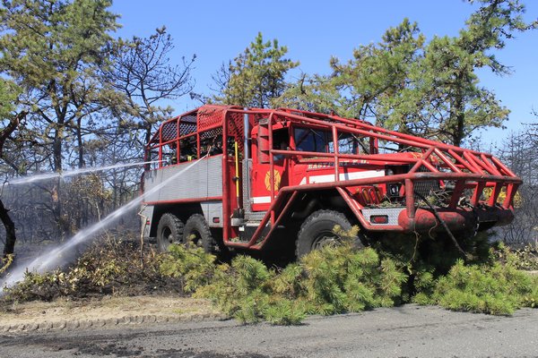 Brush trucks from various local fire departments battle a brush fire that broke out Monday morning
 in the woods along Old Riverhead Road in Westhampton. KYLE CAMPBELL