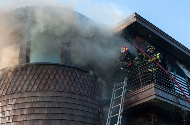 Firefighters hose down a last pocket of fire on an exterior wall. COURTESY WESTHAMPTON BEACH FIRE DEPARTMENT
