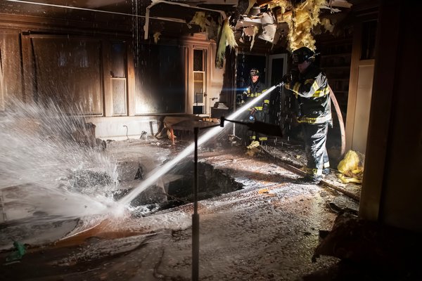 Firefighters from the Springs Fire Department battle a fire inside a house on Old Stone Highway on Sunday afternoon.  Michael Heller