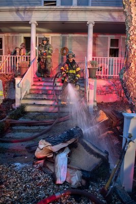 Firefighters from the Springs Fire Department battle a fire inside a house on Old Stone Highway on Sunday afternoon. MICHAEL HELLER