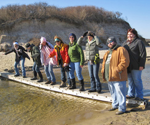 Hikers crossing a rivulet on the beach by means of a ladder