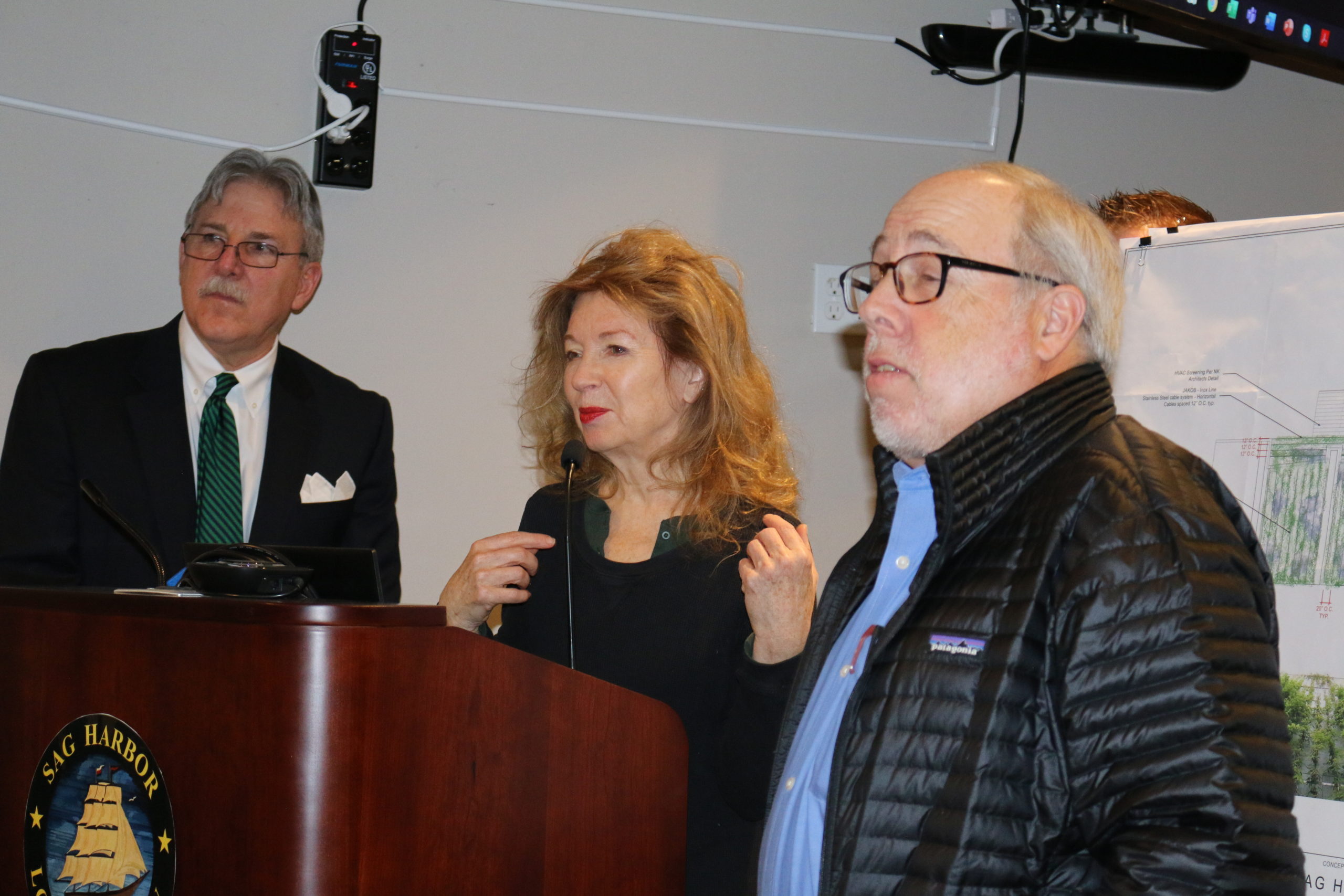 Sag Harbor Cinema Arts Center attorney Christopher D. Kelley, left, with board chair April Gornik and landscape architect Edmund Hollander addressing the Historic Preservation and Architectural Review Board at the January 9 hearing on its plan to relocate and screen HVAC equipment on the cinema roof. 