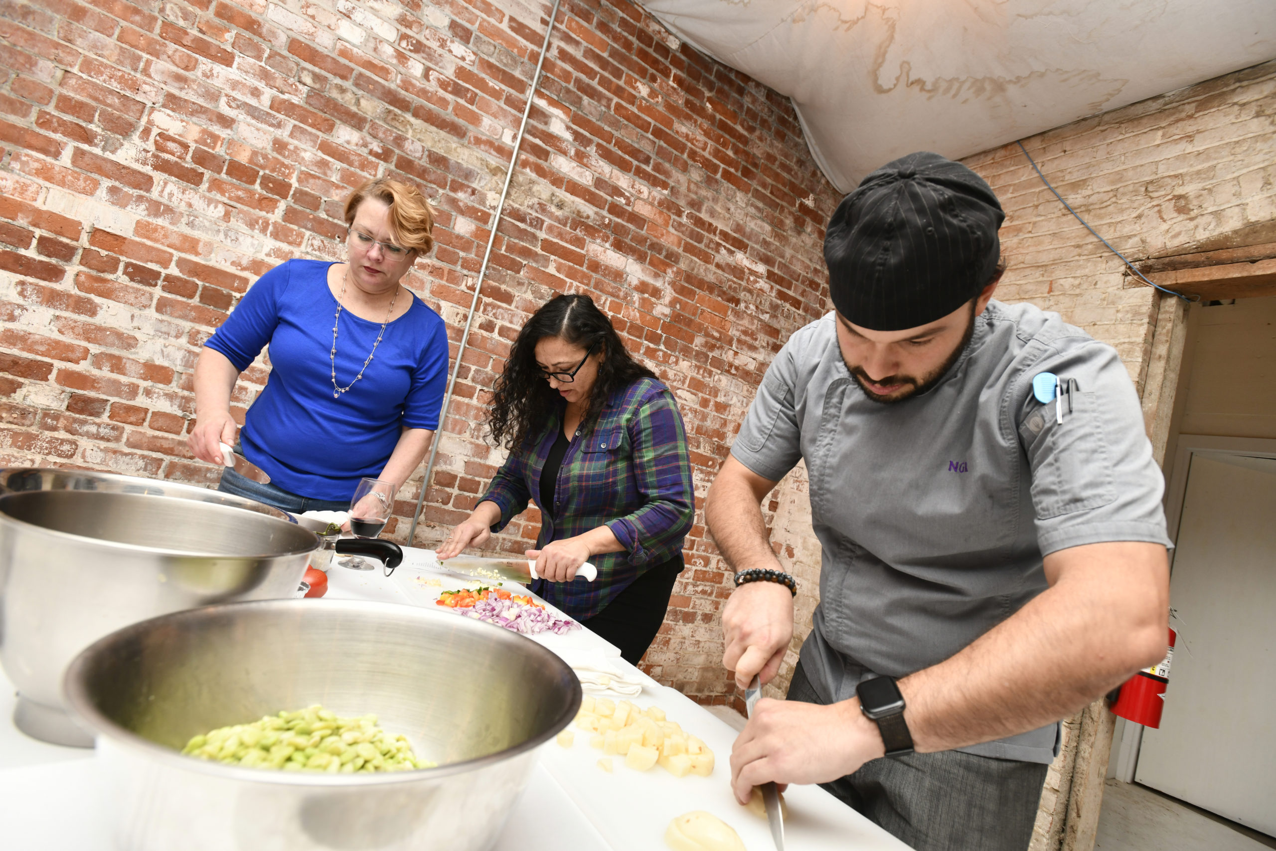 Chef Nicolas Reisini, forground, works with students Lisa Westfall and Marilyn Cruz.