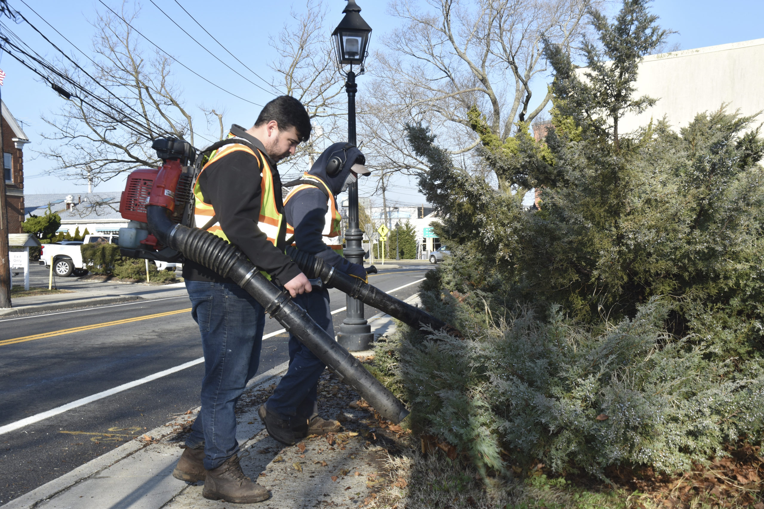 Sag Harbor Village workers, seen here cleaning up a village parking lot, would be required to comply with a seasonal ban on the use of gas leaf blowers being considered by the village board.     STEPHEN J. KOTZ