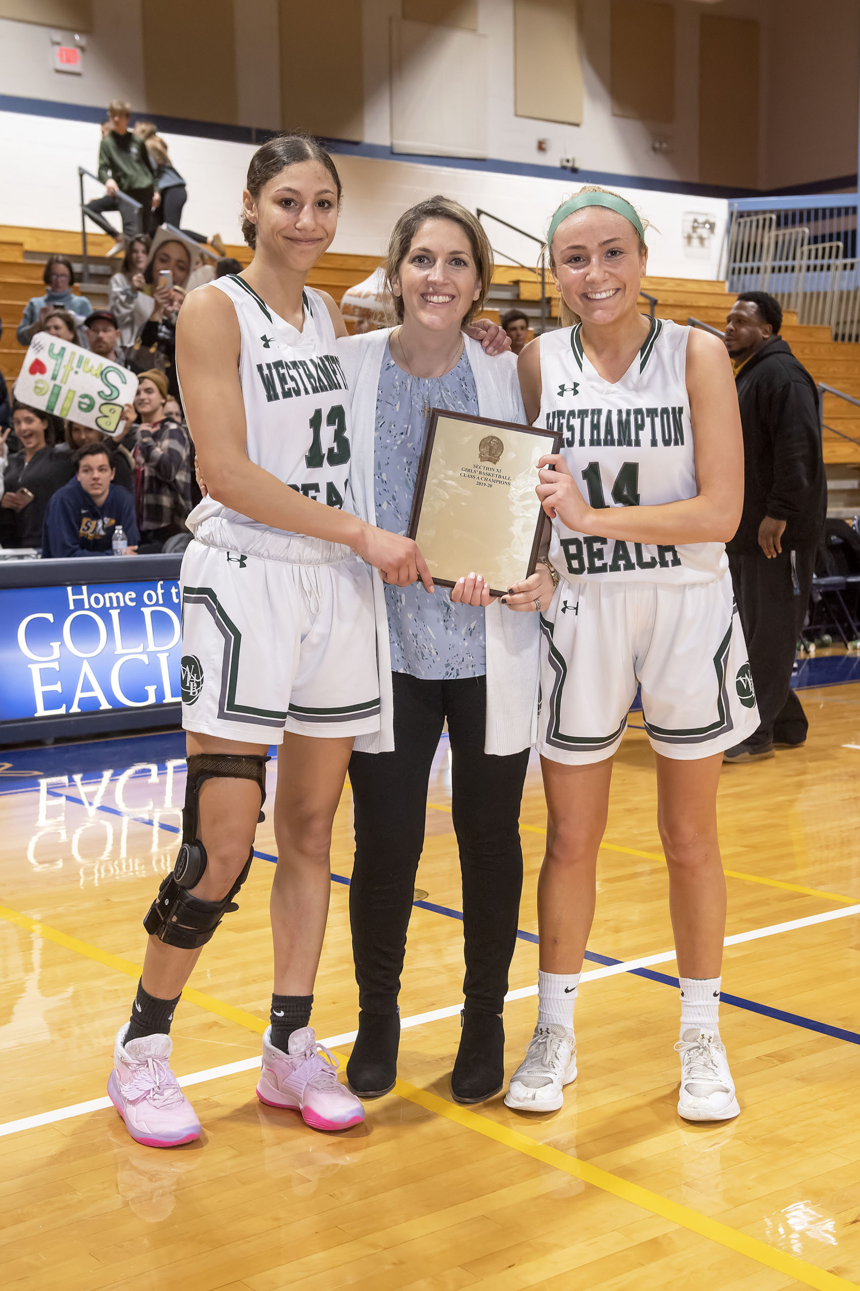 Westhampton Beach senior captains Layla Mendoza, left, and Isabelle Smith with head coach Katie Peters and the Suffolk County Class A Championship plaque.