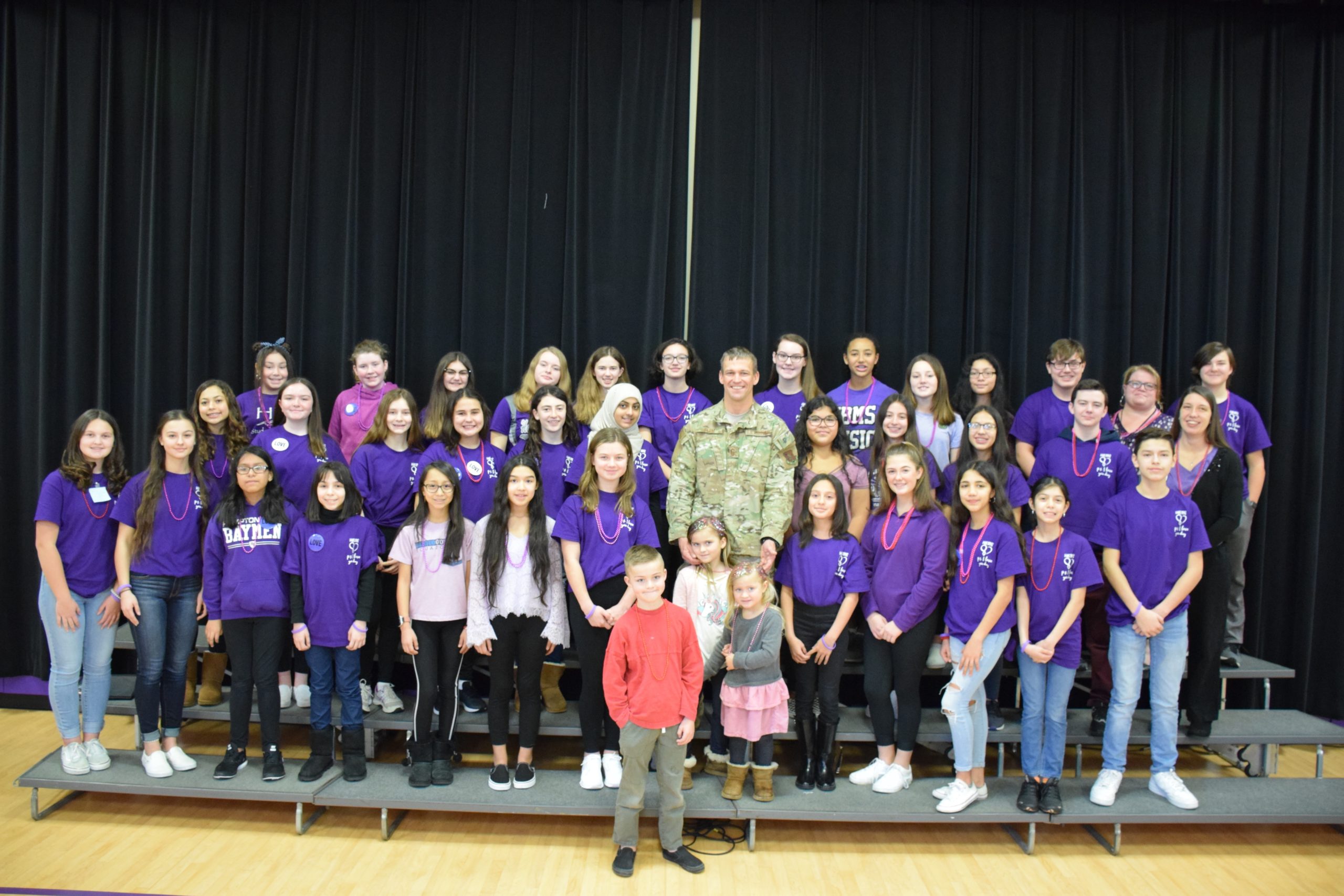 Hampton Bays High School students honored Senior Master Sergeant Erik S. Blom during a flag ceremony on February 14. With him are his children, Ryder, Sydney and Taylor, surrounded by the school's chorus. 