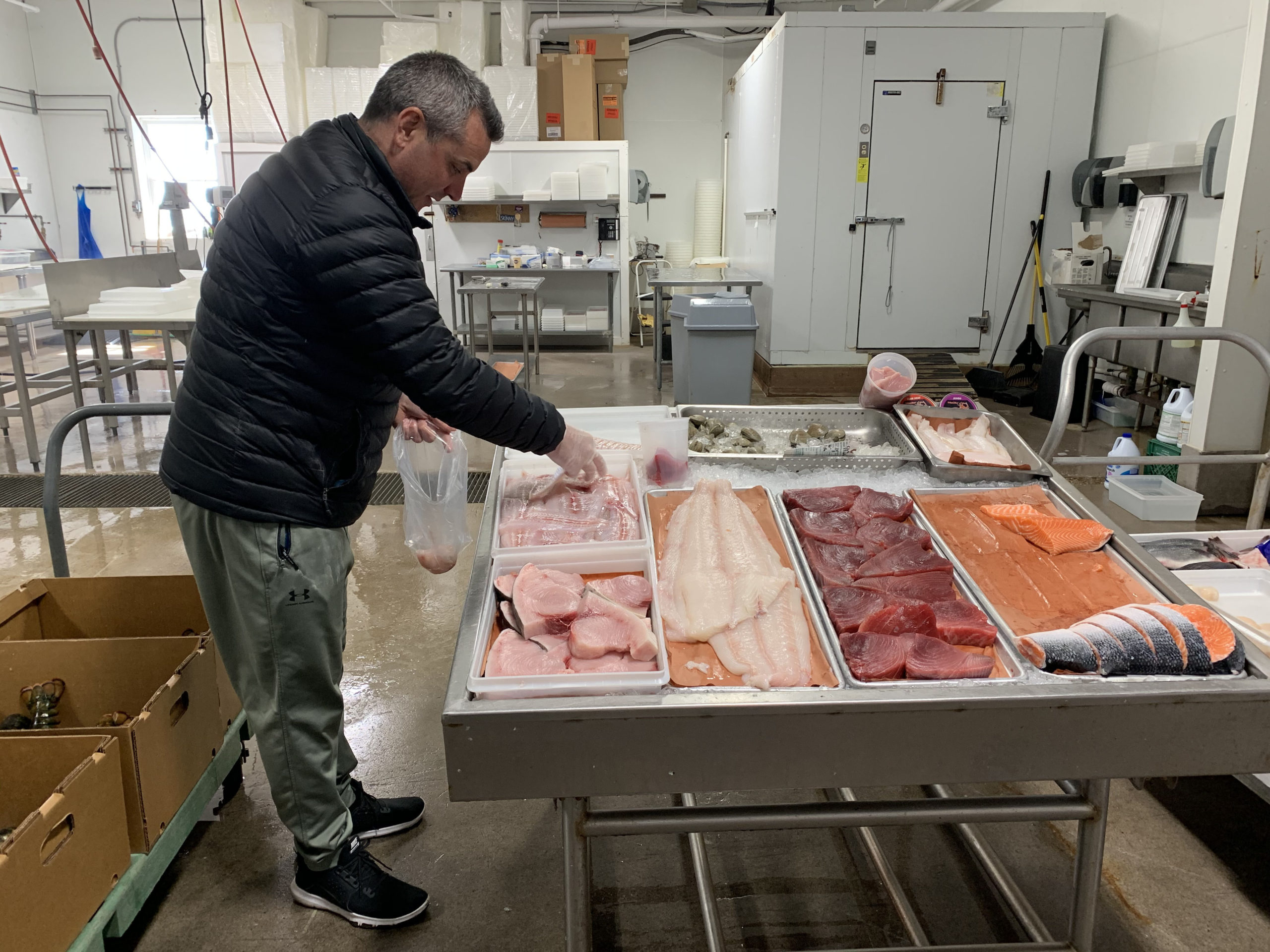 Asa Gosman serves customers form a makeshift retail seafood stand at Gosman’s Fish Market in Montauk on Sunday.    GAVIN MENU