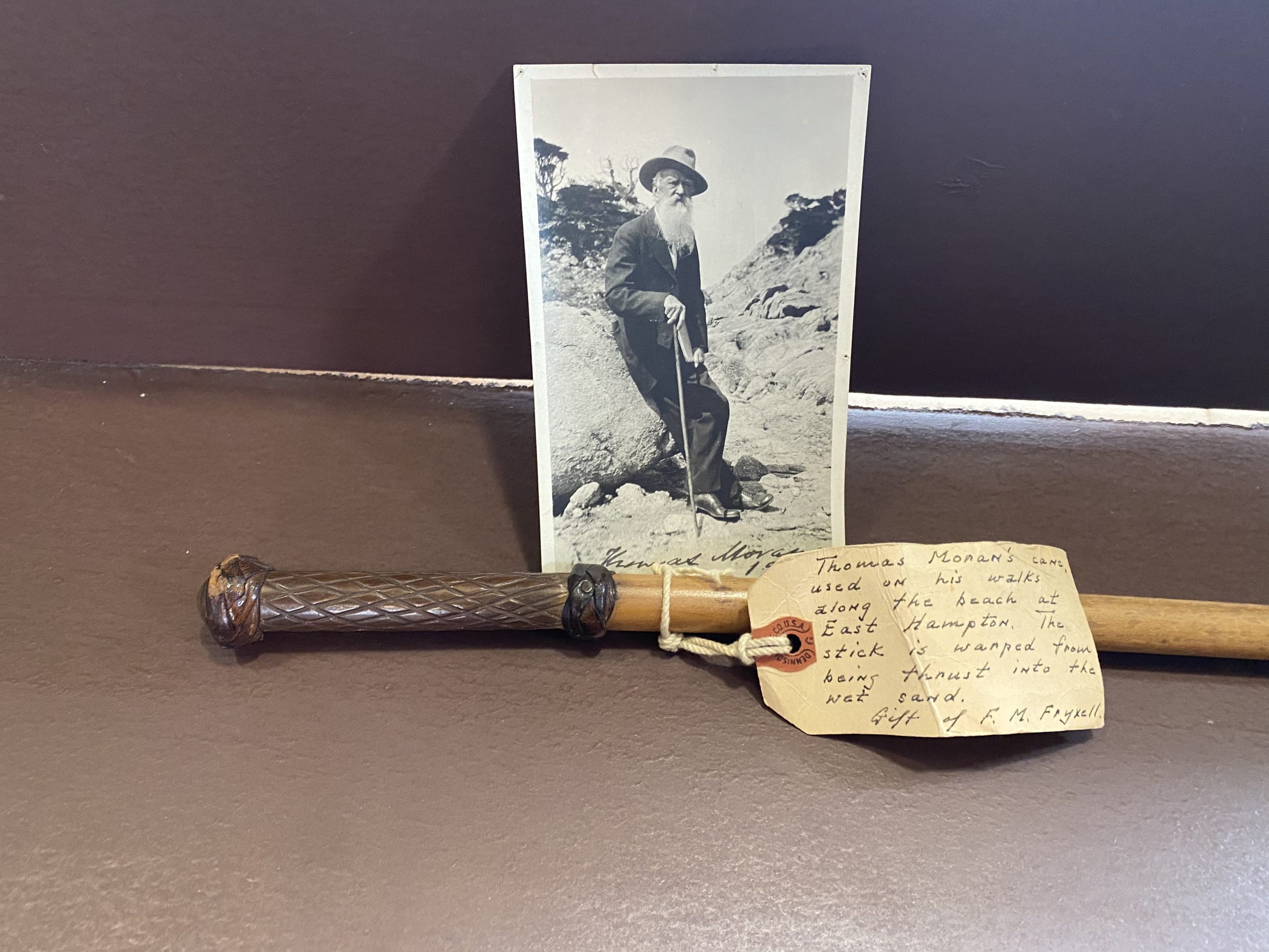 Thomas Moran's walking stick, which he holds in a photograph taken in Monterey, California, 1919. His friend geologist Fritioff Fryxell included a note that he believed the cane was warped from Moran's walks on wet sand. 