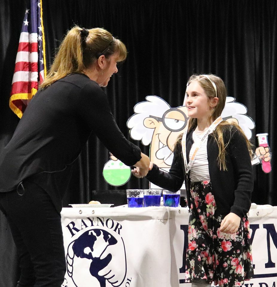 Raynor Country Day School third-grader Lilyanna Webste, recieves her medal from science teacher Elaine Marshall at Raynor Country Day School's recent Science Fair.