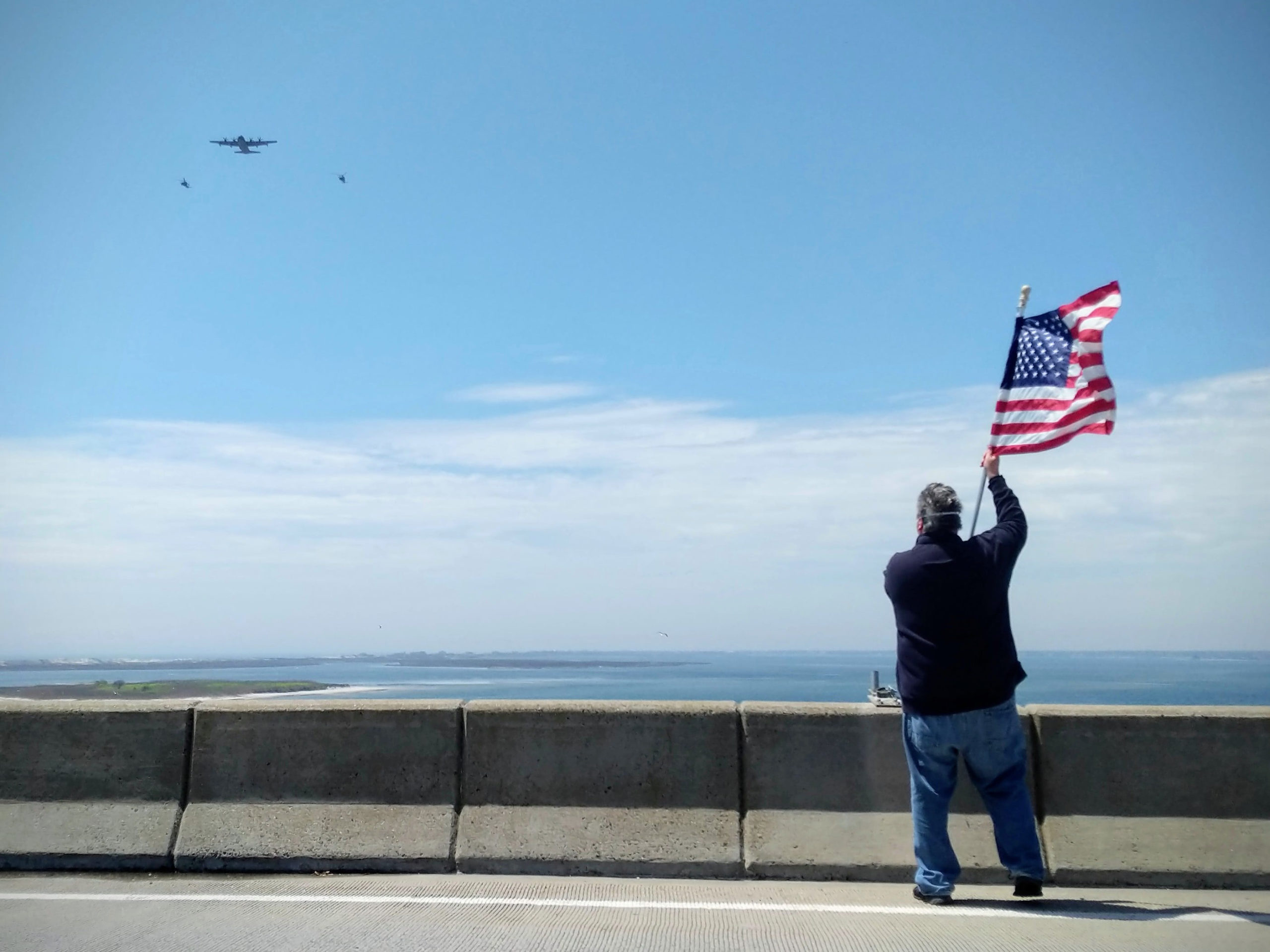 Hampton Bays resident Patrick Ottati waves an American Flag on Ponquogue Bridge during the 106th Rescue Wing Flyover Saluteon Firday. The 106th Rescue Wing organized a flyover of Long Island hospitals and health care facilities to show appreciation and support for frontline workers.    Courtesy NY Air National Guard Senior Airman Daniel Farrell