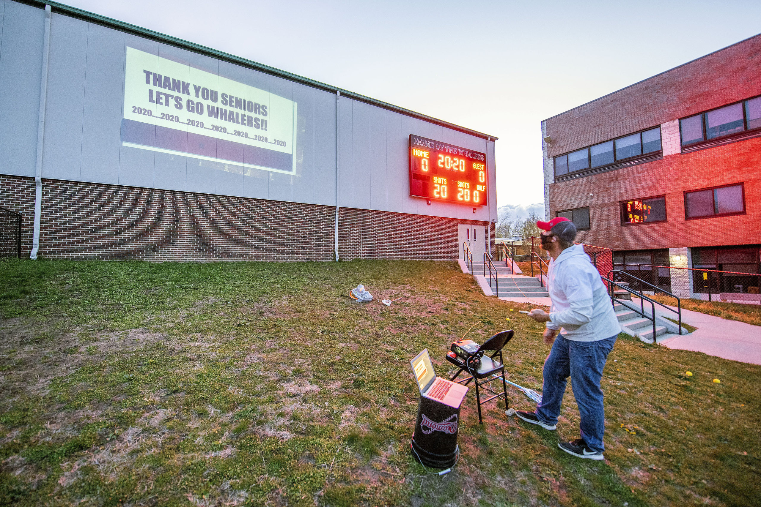 Pierson Athletic Director Eric Bramoff sets up the scoreboard and a slideshow in preparation for a tribute to the Pierson High School senior athletes in the field behind the school on Friday night.