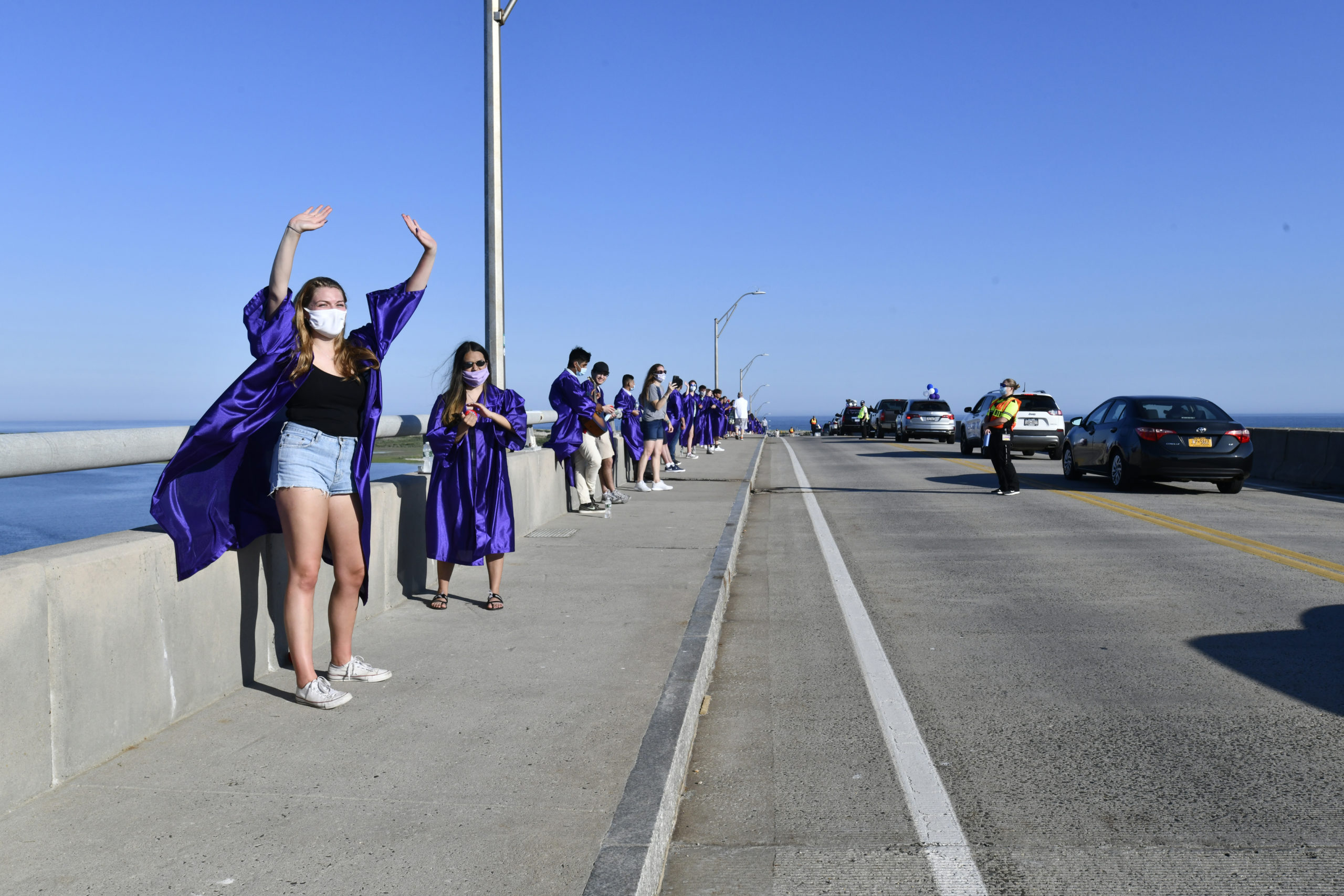 Hampton Bays graduate Julia Heming waves as friends and family members drive over the Ponquougue Bridge to recognize the graduates.  DANA SHAW