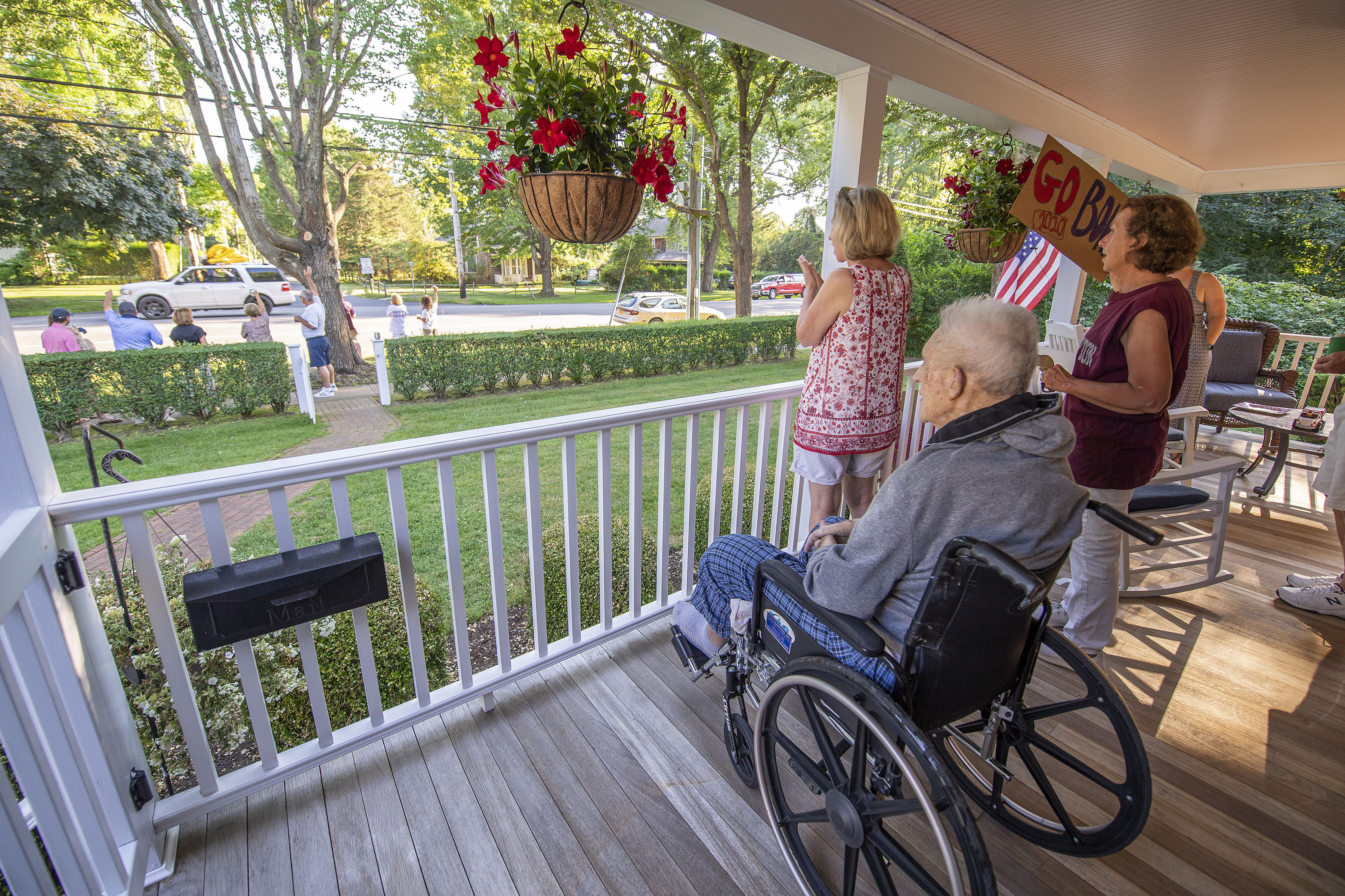 Eighty- three-year-old John McGuirk, Sr. watches the parade of passing East Hampton High School graduates from his front porch on Newtown Lane following the 2020 graduation ceremony at the East Hampton High School on Friday.