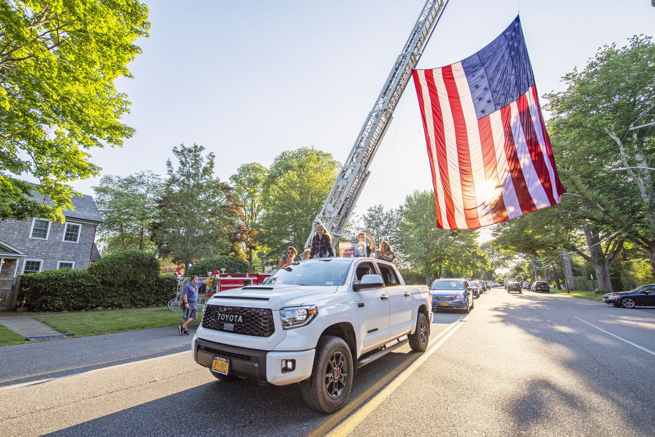 A newly-graduated East Hampton High School senior pass underneath a large American flag hoisted by EHFD Hool & Ladder Co.#1 in honor on the graduates on Newtown Lane following the 2020 graduation ceremony at the East Hampton High School on Friday.