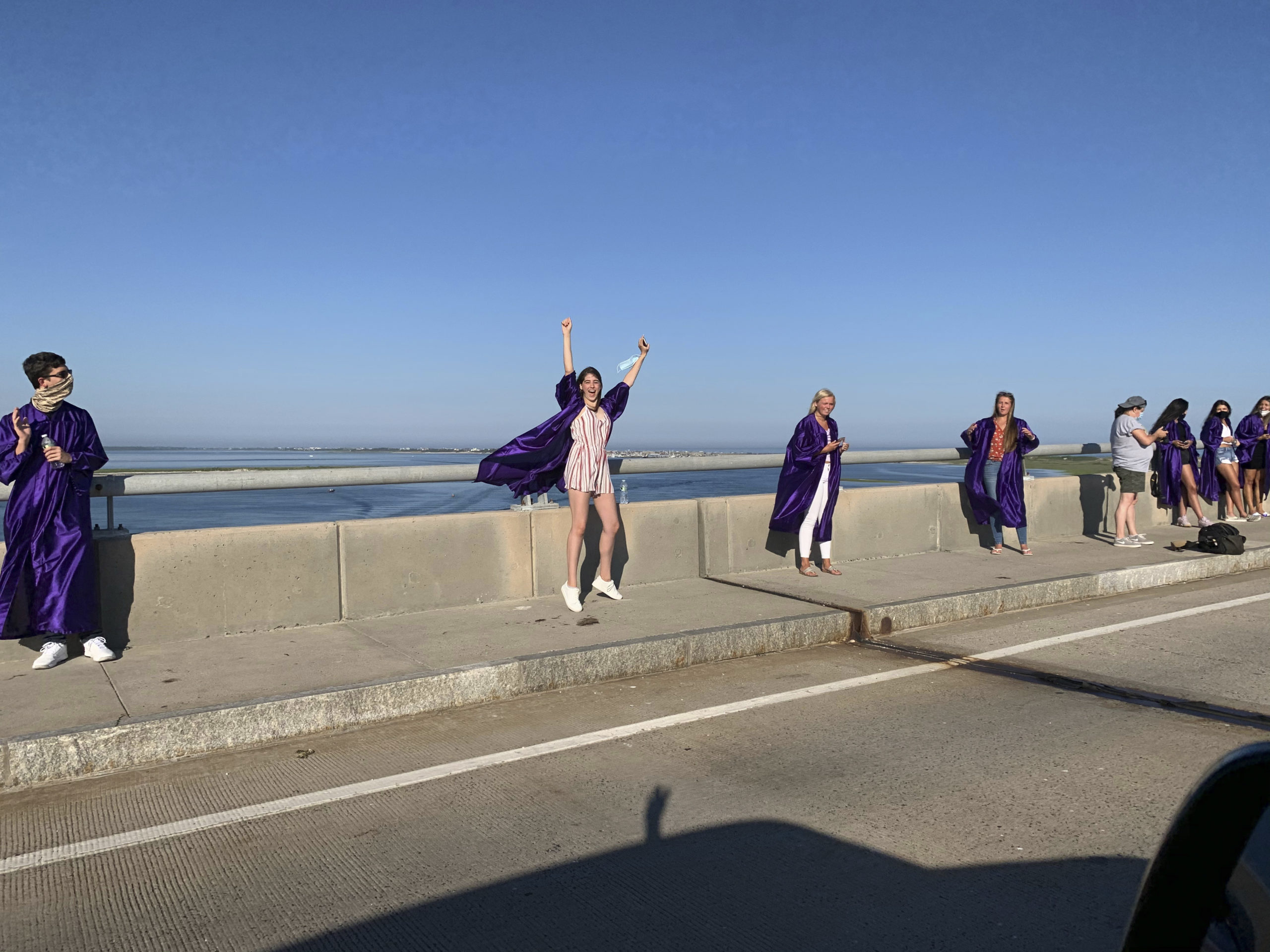 Hampton Bays graduates gathered on the Ponquogue Bridge in Hampton Bays on Monday evening as friends and family drove by to congratulate them. MONICA HANES