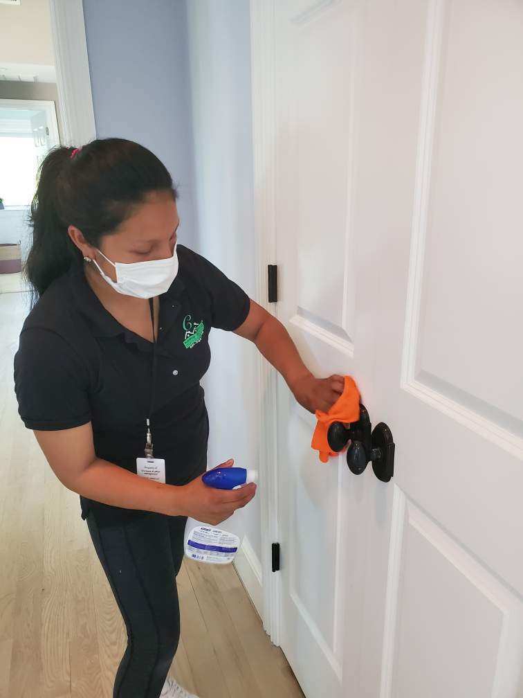 Irma of C's Home & Office Management Disinfects a doorknob.