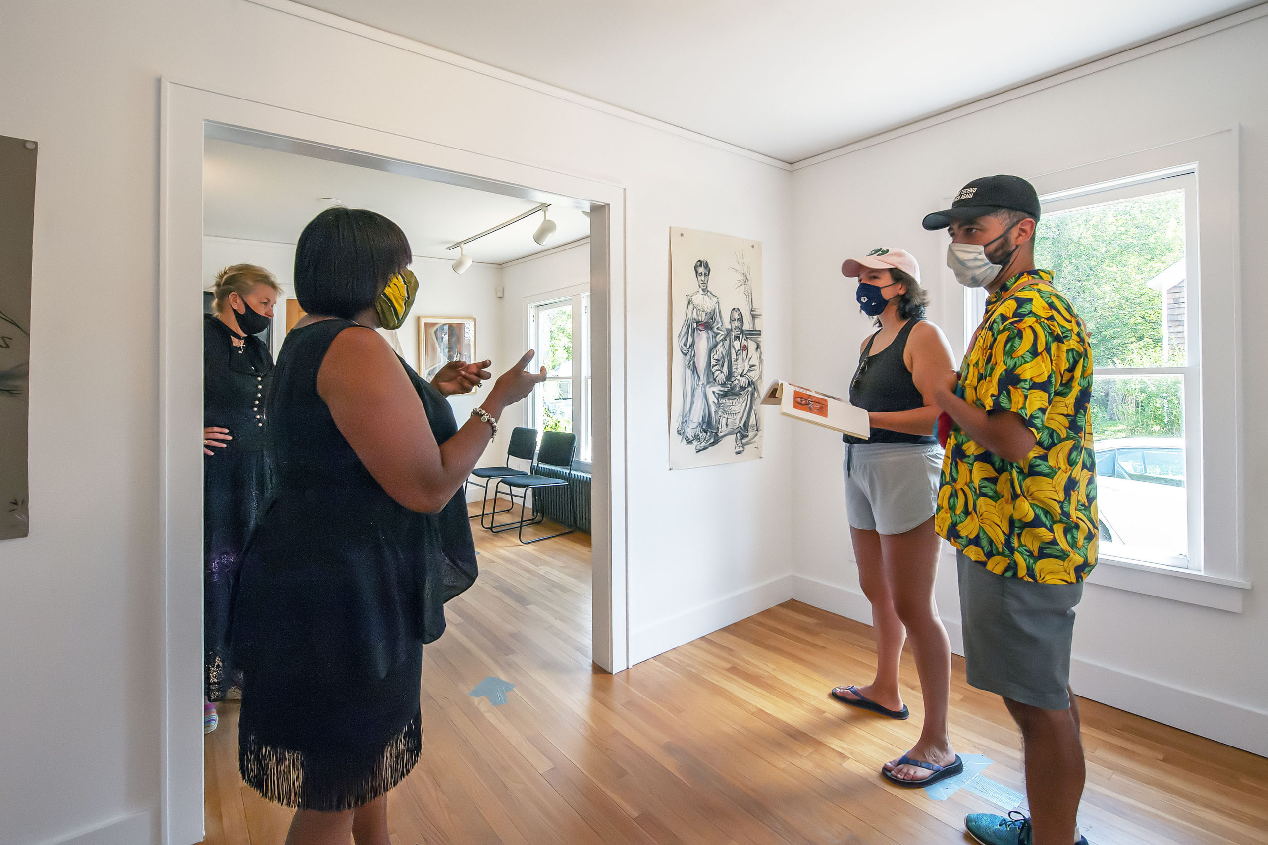 As artist Sabina Streeter looks on AS curator Dr. Georgette Grier of the Eastville Historical Society speaks about her artwork to visitors just prior to the opening of her exhibition at the Society's Heritage House on Saturday.   MICHAEL HELLER
