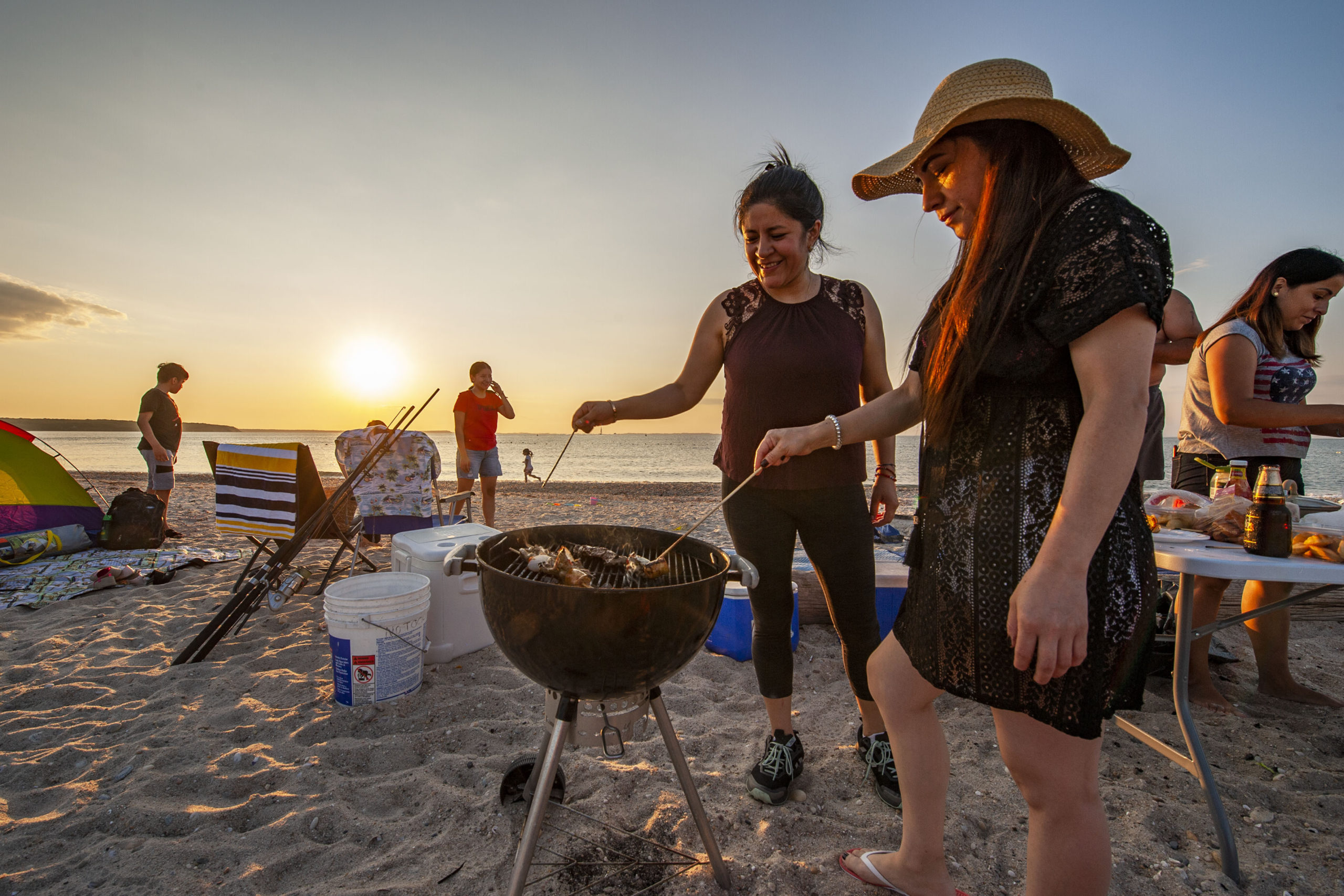 Nancy Vinueza cooks up some Shish Kebab on the grill as she joins friends and family in a July 4th celebration as the sun goes down at Maidstone Park Beach on Saturday evening.  MICHAEL HELLER