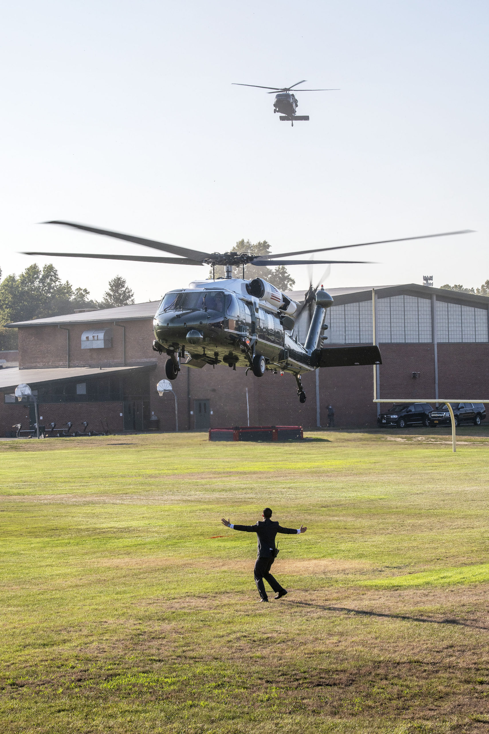 A plainclothes Marine guides one of the presidential Blackhawk helicopters as it lands. Members of the Southampton Fire Department went on standby to provide fire protection as President Donald Trump arrived and departed from the athletic fields behind Southampton High School during his visit to the Hamptons on Saturday.         MICHAEL HELLER
