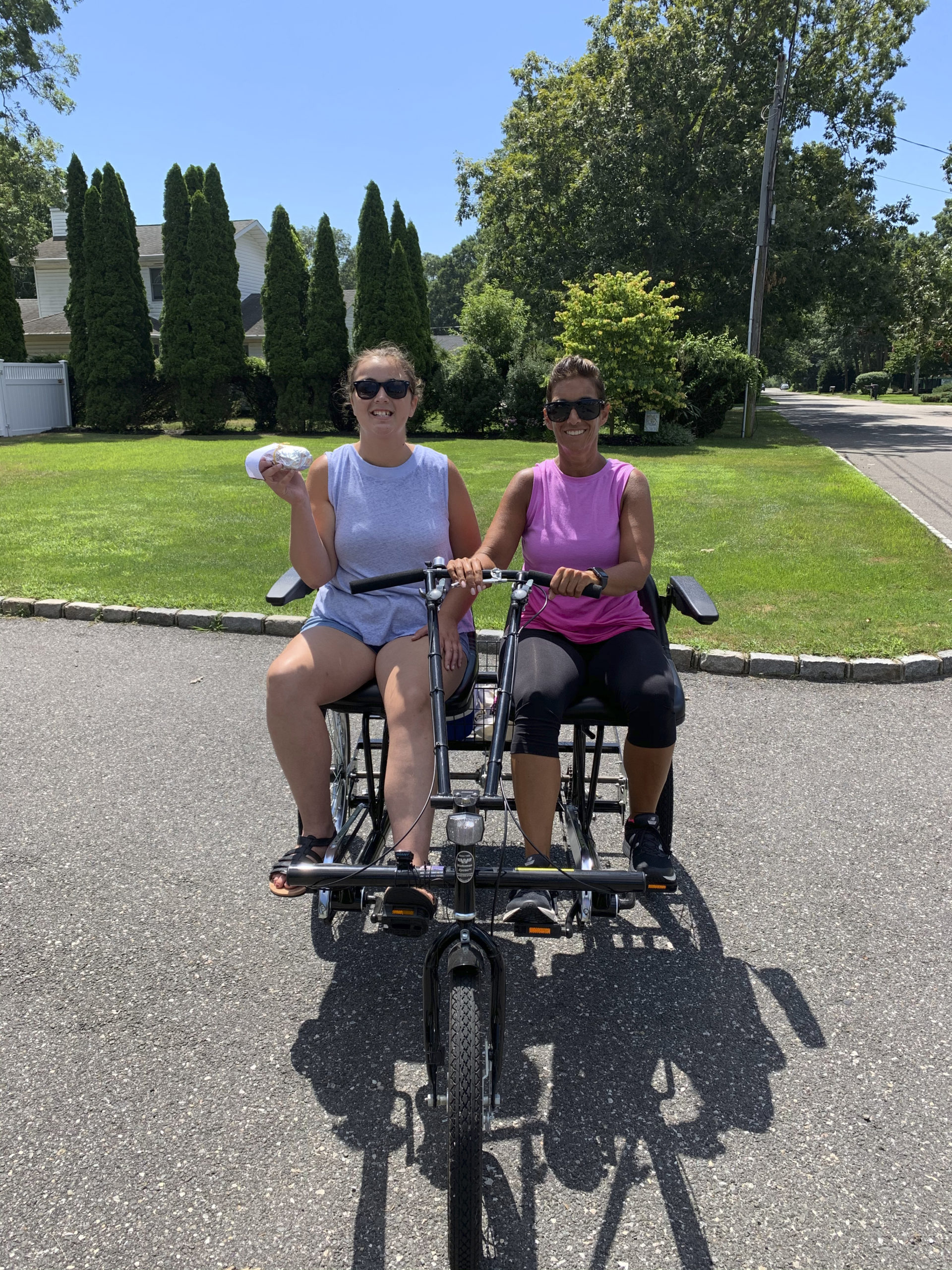 Anna Tuzzolo, 16, and her mother, Patty Tuzzolo, on their side-by-side bike for two, delivering homemade baked goods to friends in their Shinnecock Shores neighborhood in East Quogue. They are participating in the annual Bike To The Beach fundraising event for the Flying Point Foundation, which is being done virtually because of the pandemic. The foundation supports local families with children with autism. 