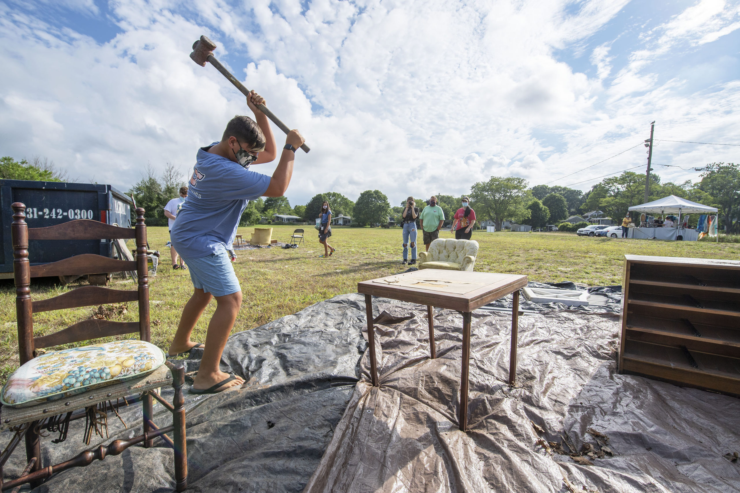 Cole Warren takes a sledgehammer to a card table during the Rage for Canines fundraiser that took place at Havens Beach on Friday evening.     MICHAEL HELLER