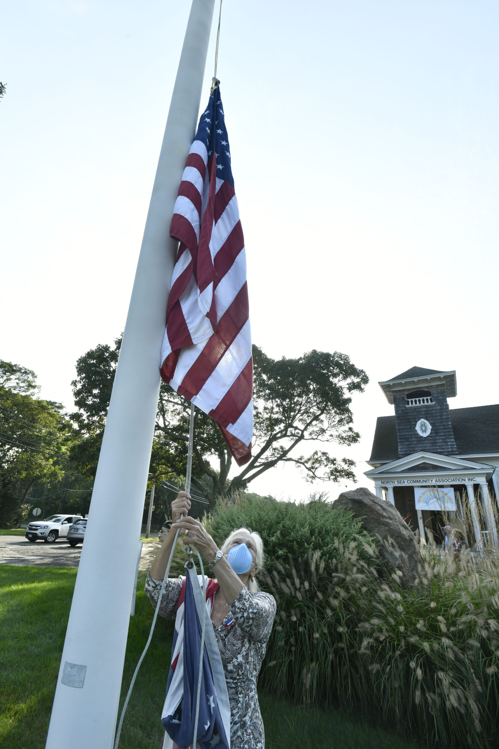 Barbara Fair lowers the flag to half-staff on Friday morning at the North Sea Community House.