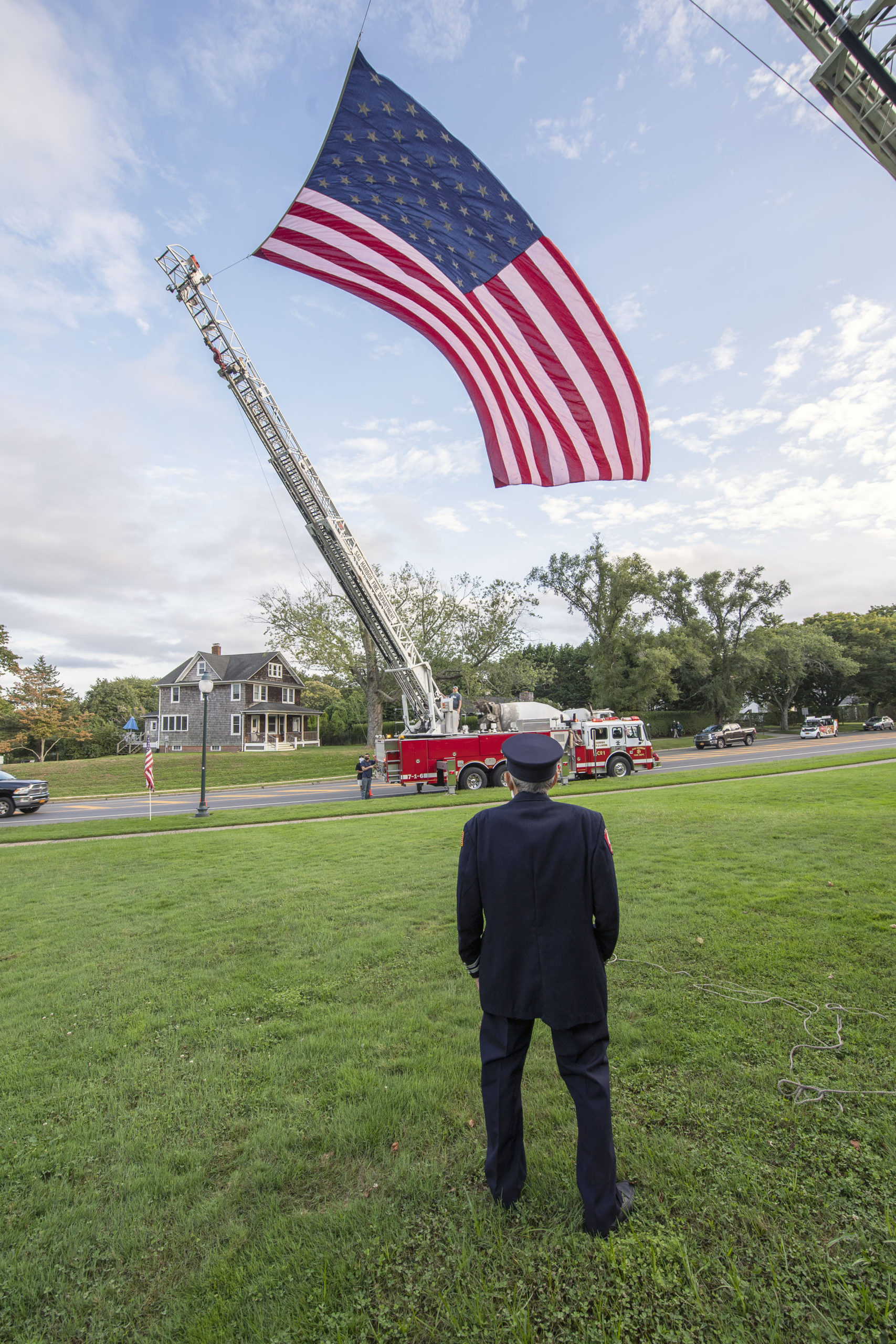 East Hampton Fire Department 50+ year member Joseph DeCristofaro looks up at a large american flag hoisted by EHFD and Sag Harbor FD ladder companies as members of the East End Fire, EMS and Police Departments held a memorial service on the village green in East Hampton commemorating the 19th anniversary of the September 11 attacks.
