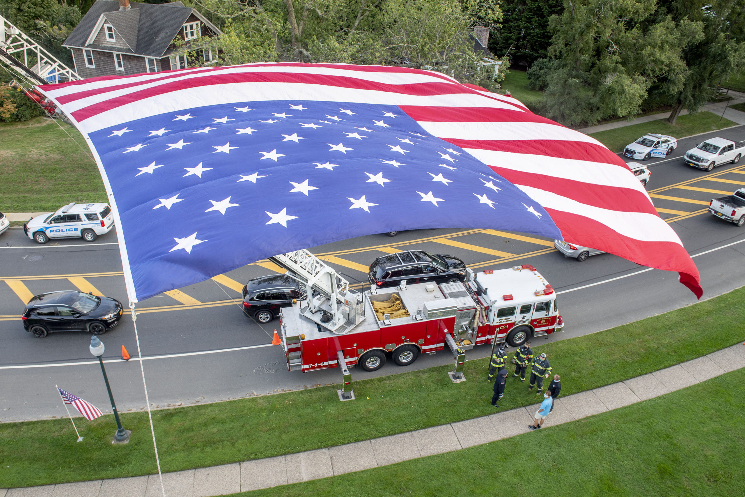 Sag Harbor firefighters gather under a large american flag hoisted by East Hampton and Sag Harbor ladder companies as members of the East End Fire, EMS and Police Departments held a memorial service at the village green in East Hampton commemorating the 19th anniversary of the September 11, 2001 terrorist attacks.