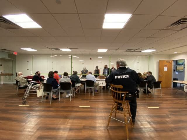 Candidates, their representatives and attorneys set up behind a plexiglass shiled to begin the arduous count of absentee ballots, as a village police officer looks on. DANA SHAW