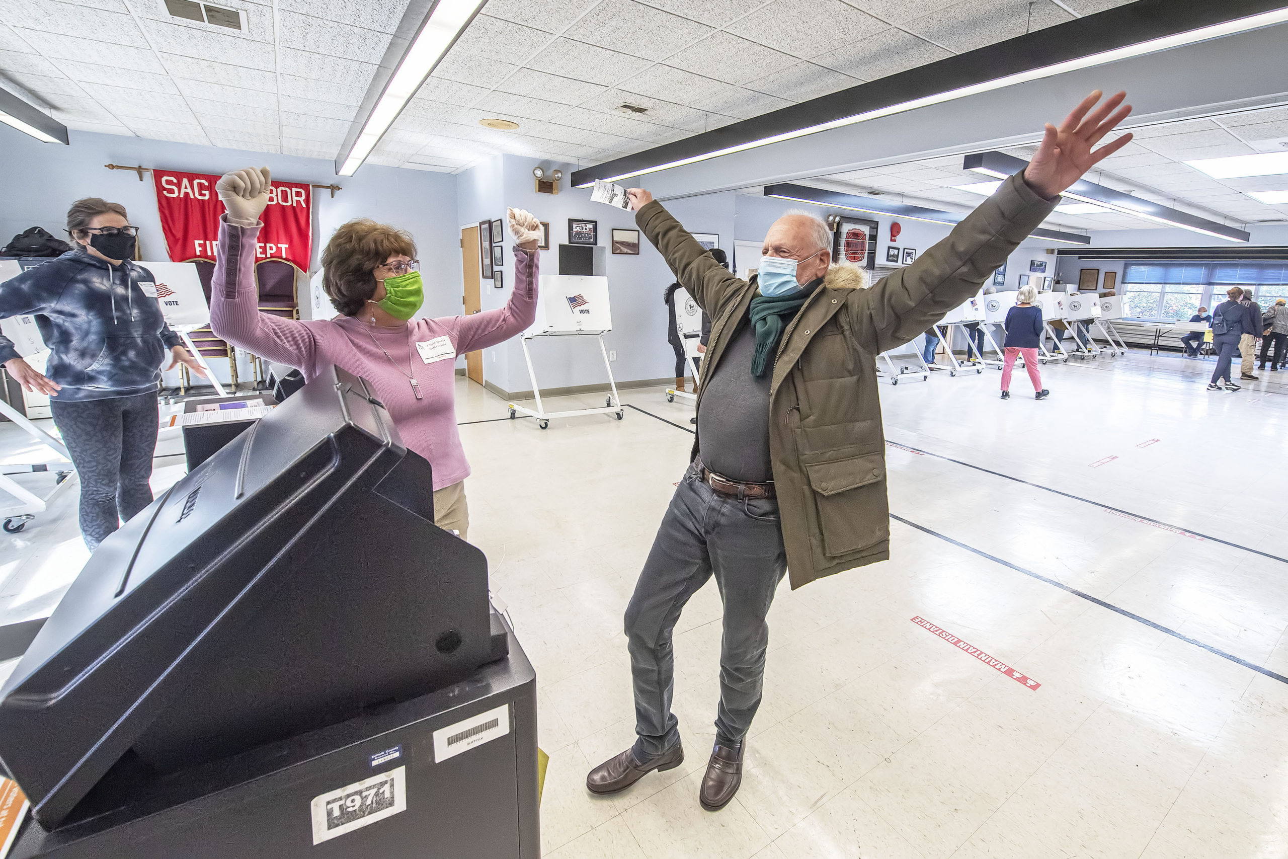 Poll Worker Caroline Cutaia celebrates after helping Billy Sonenfield cast his ballot at the polling station at the Sag Harbor firehouse on Election Day morning.  MICHAEL HELLER