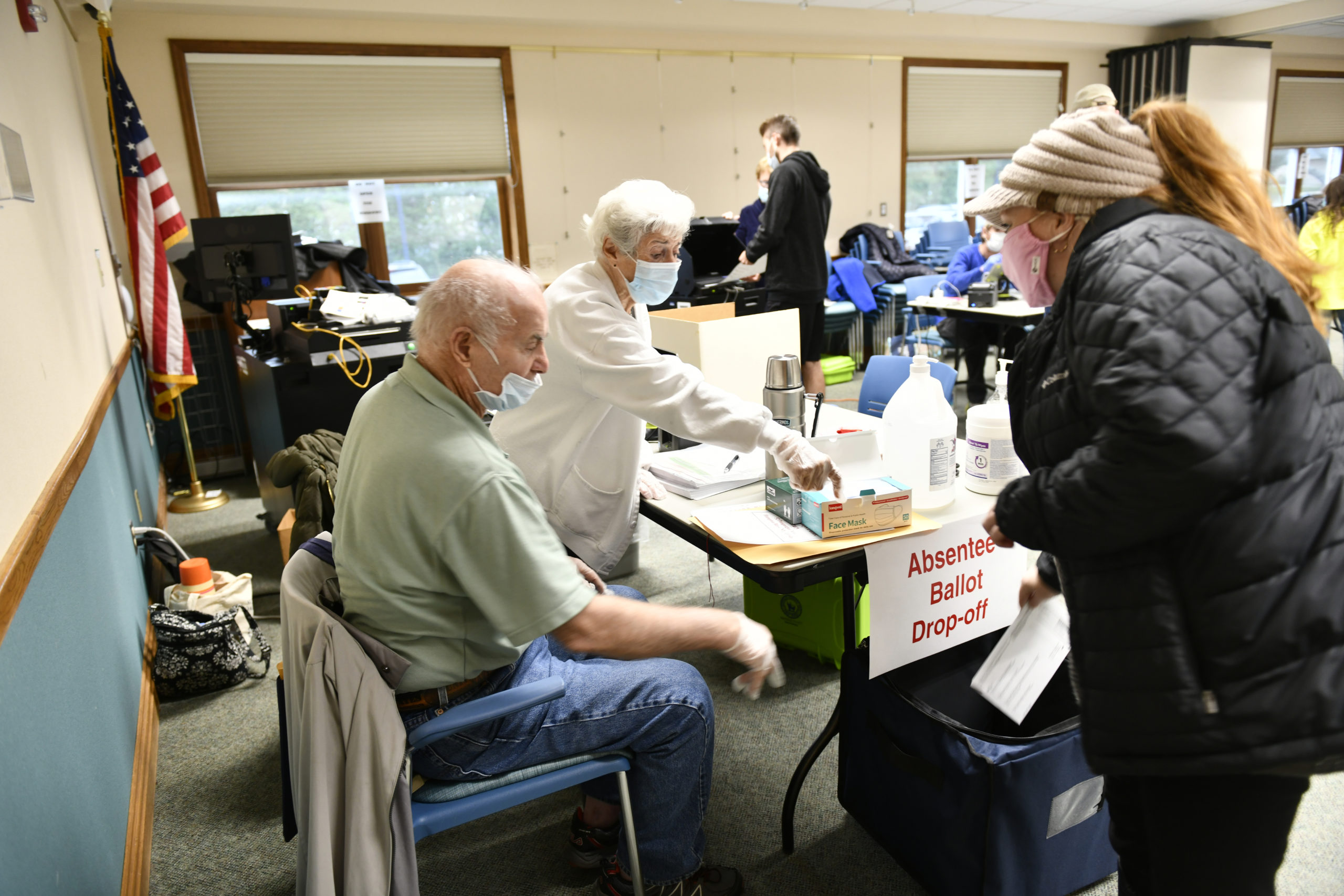 Polling Place Coordinators Mella Burke and Richard Barletta assist a voter at the Hampton Bays Library on Tuesday morning.   DANA SHAW