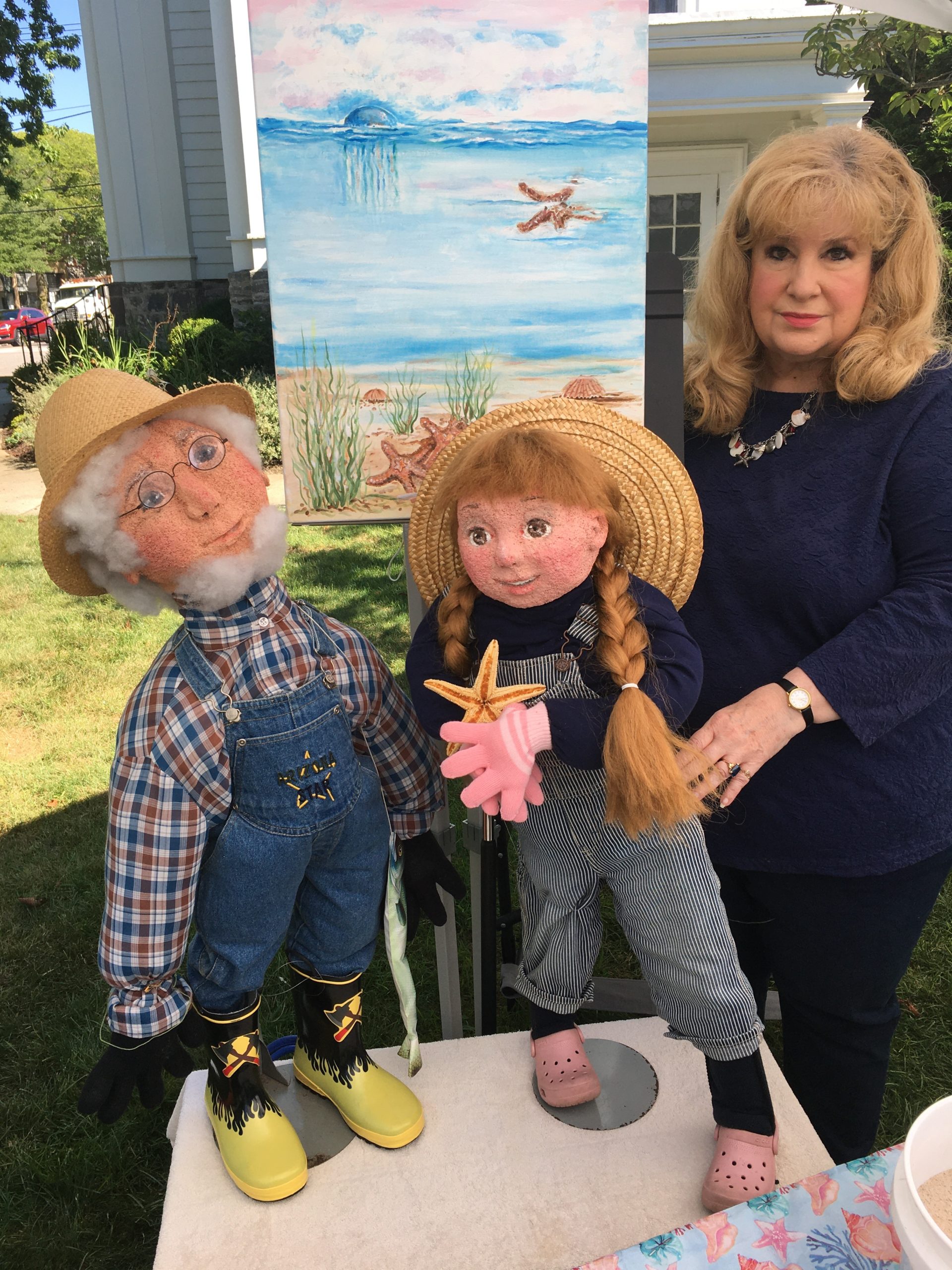 Katherine Mades with a painting and the characters from her children's story, 