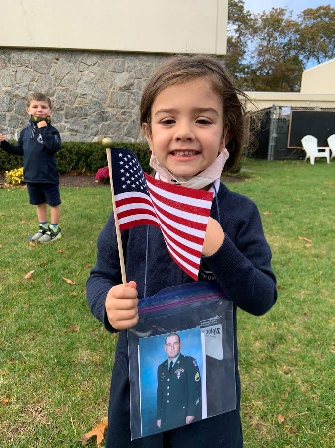 Pre-kindergarten student, Lily Crisci, celebrates the service of her uncle during Raynor Country Day SChool's annual Veterans' Day Celebration.