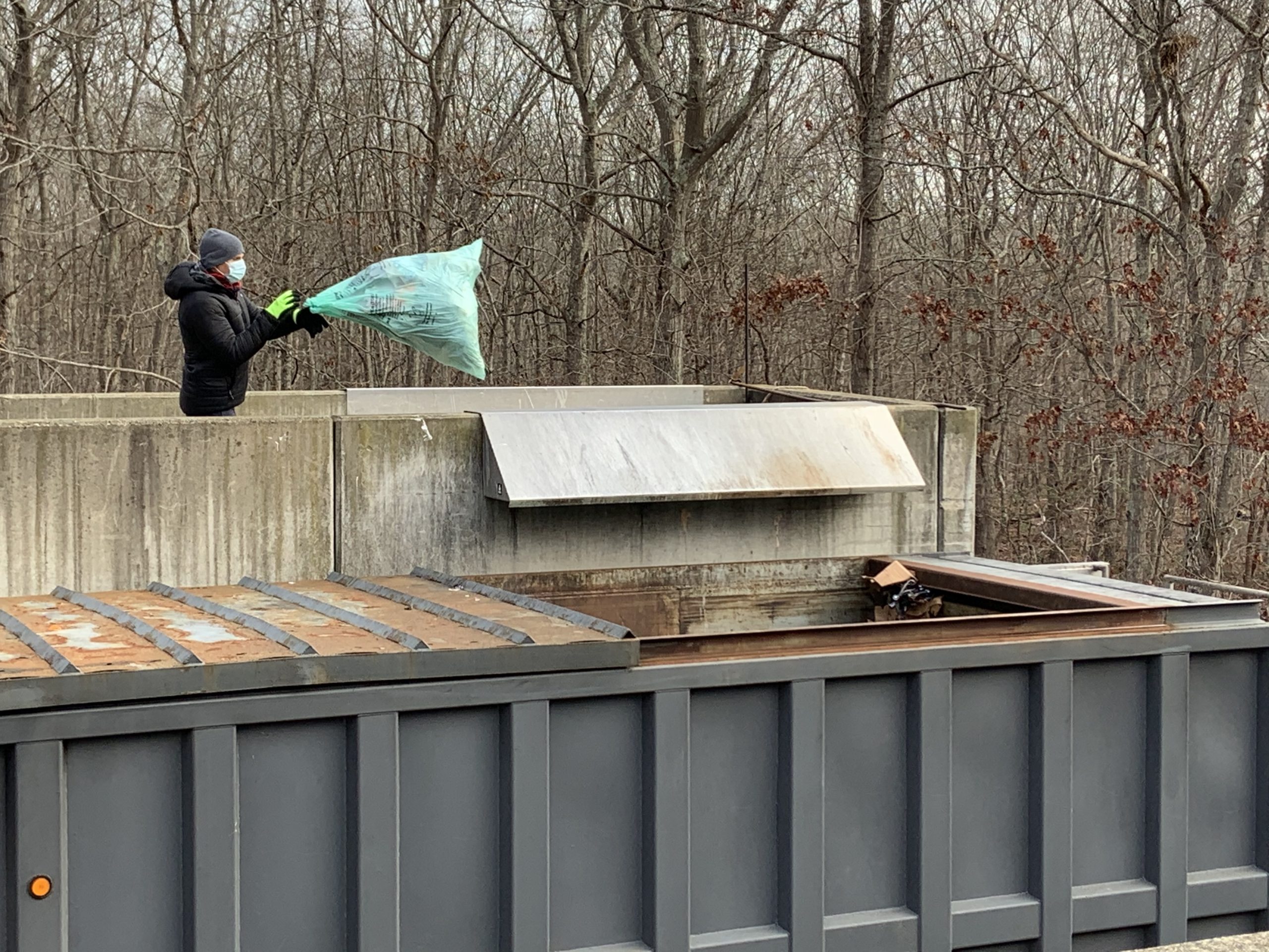 A self-hauler tosses a green bag full of nonrecyclable garbage at the Sag Harbor transfer station. STEPHEN J. KOTZ