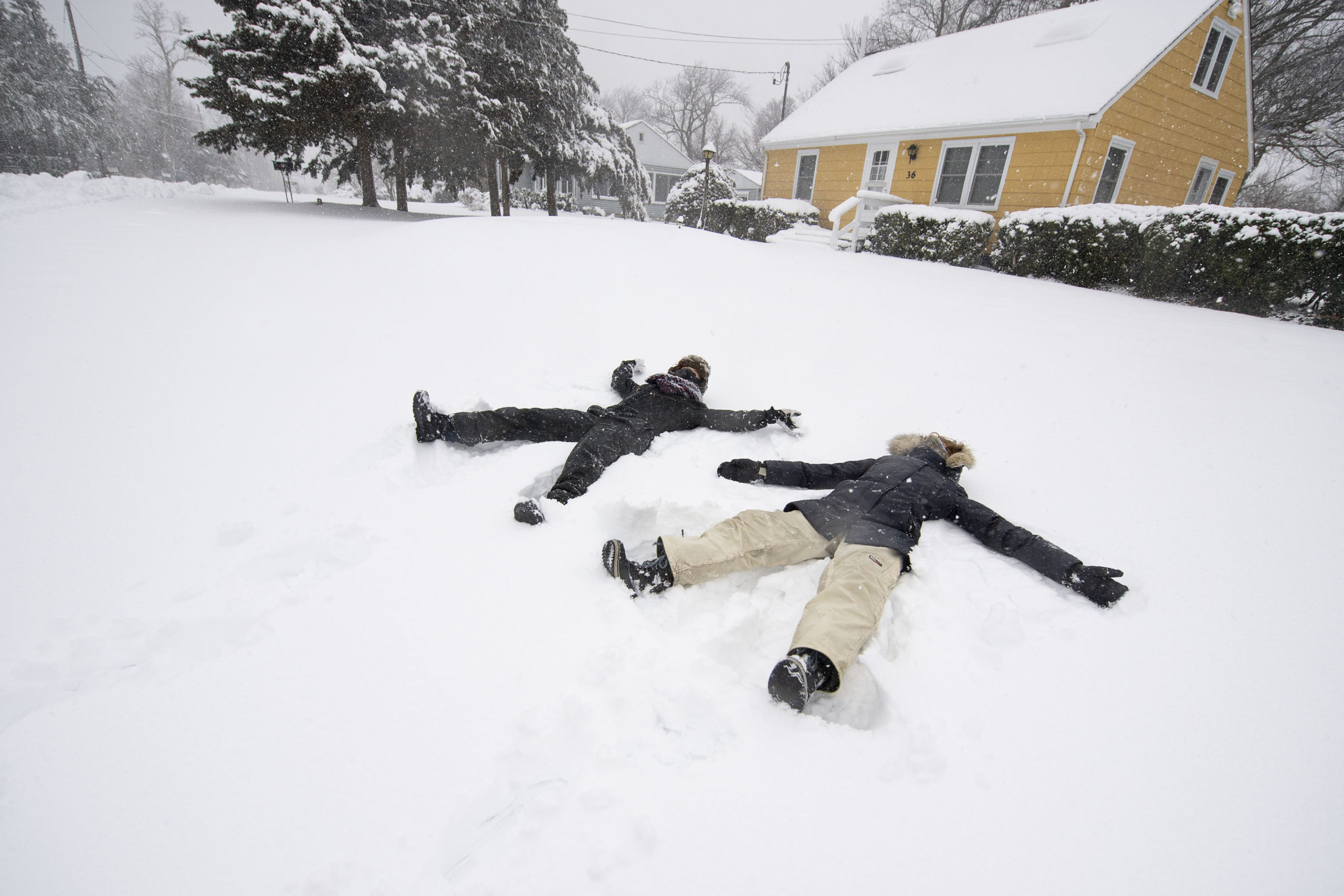 Michele Marks and her mom Jacqueline make snow angels in front of their Bay Point home during the snowstorm on Monday.   MICHAEL HELLER