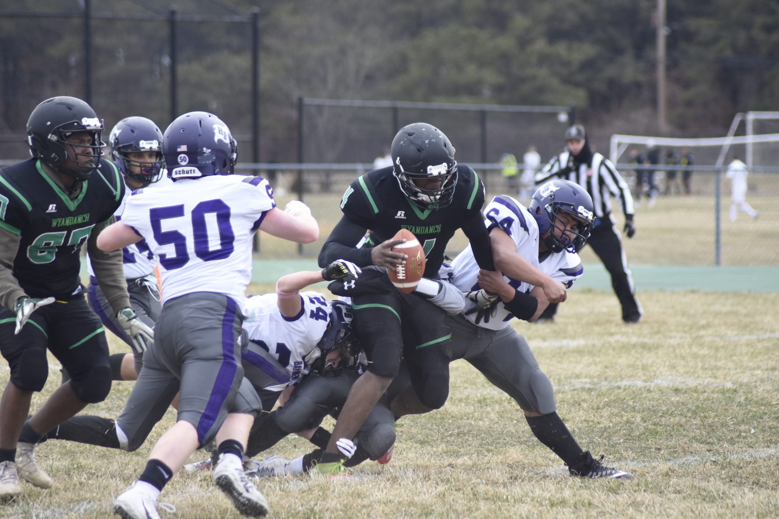 A trio of Baymen -- Alex Velasquez (64), Ben Sohtz and River Orlando -- take down Wyandanch quarterback DeAndre Smith.