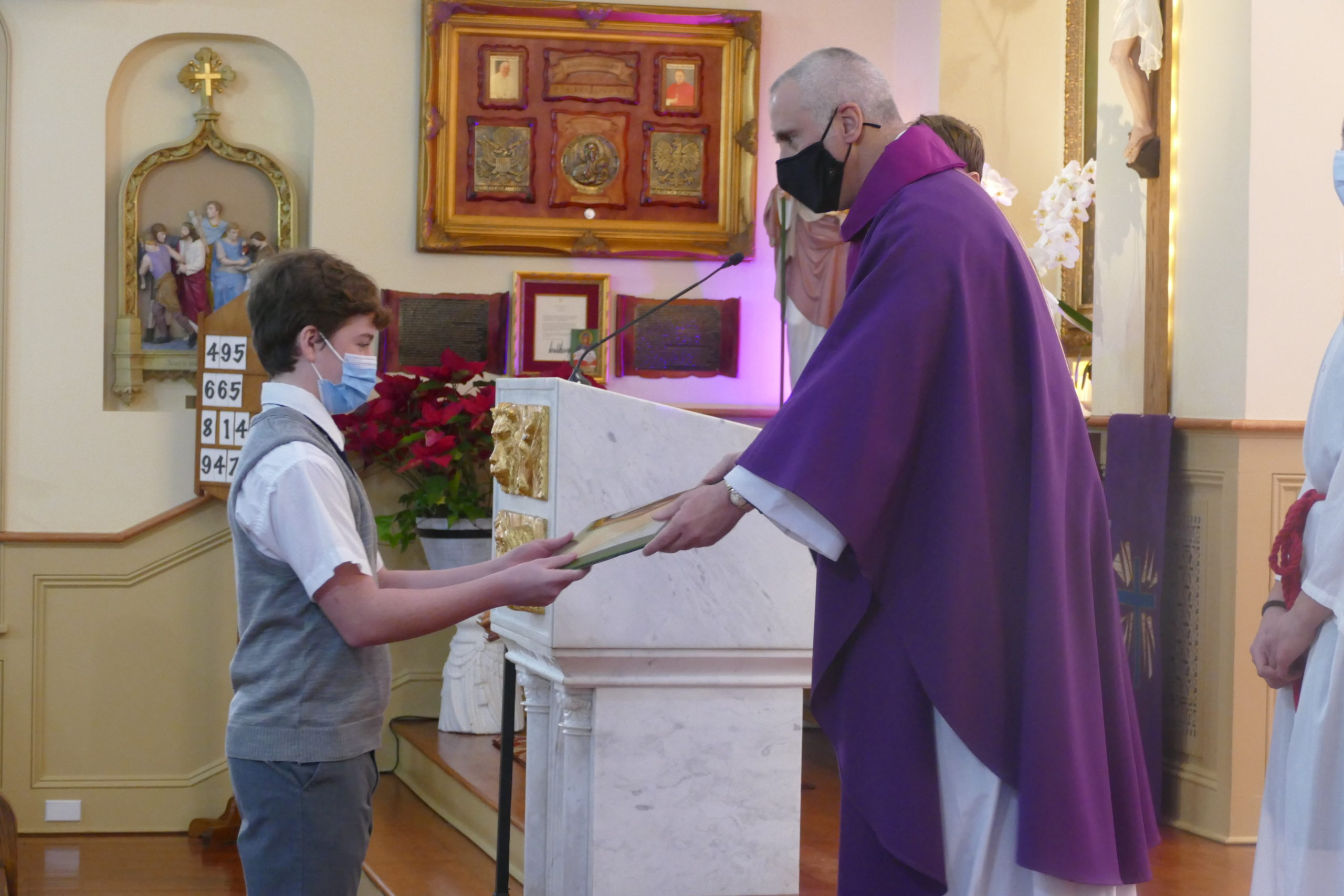 OLH Prep 8 student Jack Cantwell presents one of the offertory gifts to Father Maddaloni at the Lenten liturgy
