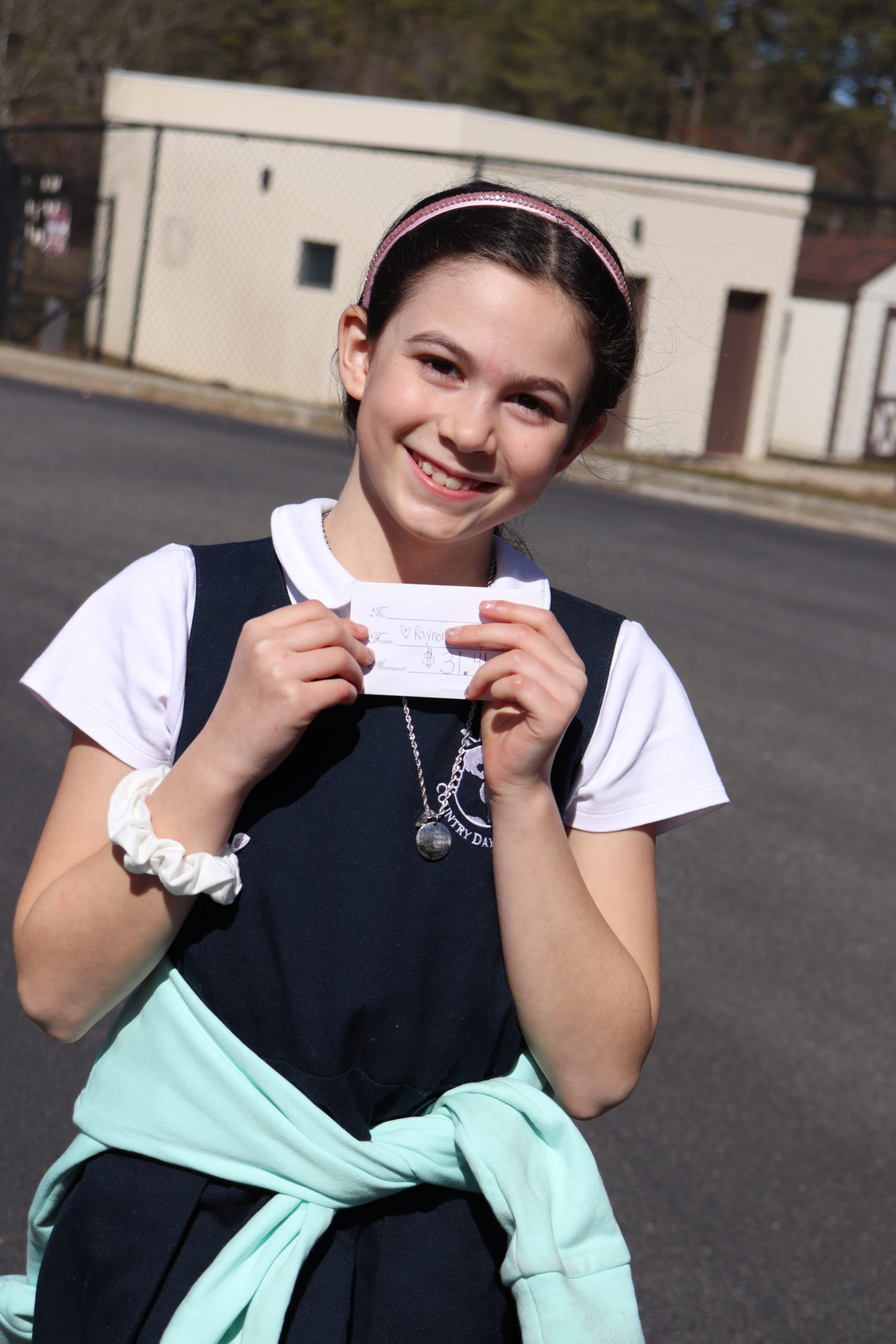 Fourth-grade student, Luna Pulver, poses proudly with her gift certificate for $31.41 of 