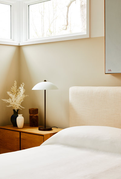 A two-tone beige wall adds warmth to a crisp guest bedroom.