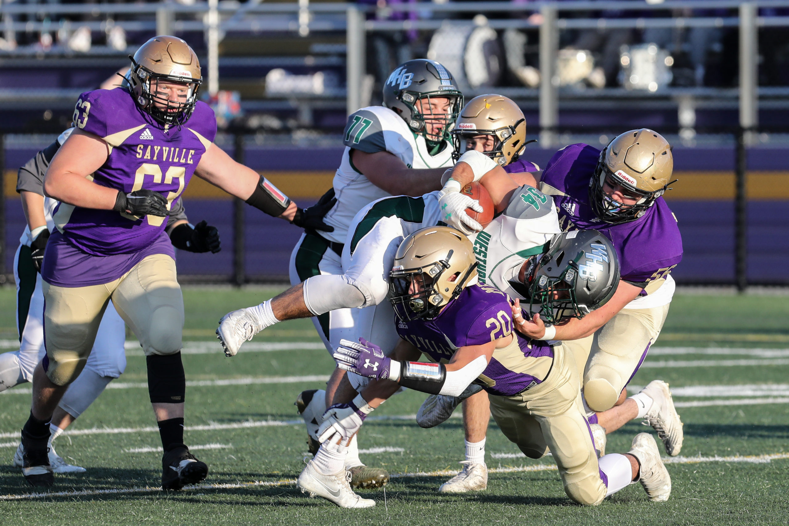 Dom Sarno of Westhampton Beach is tackled Sayville's C. J. Messina and another Golden Flash.