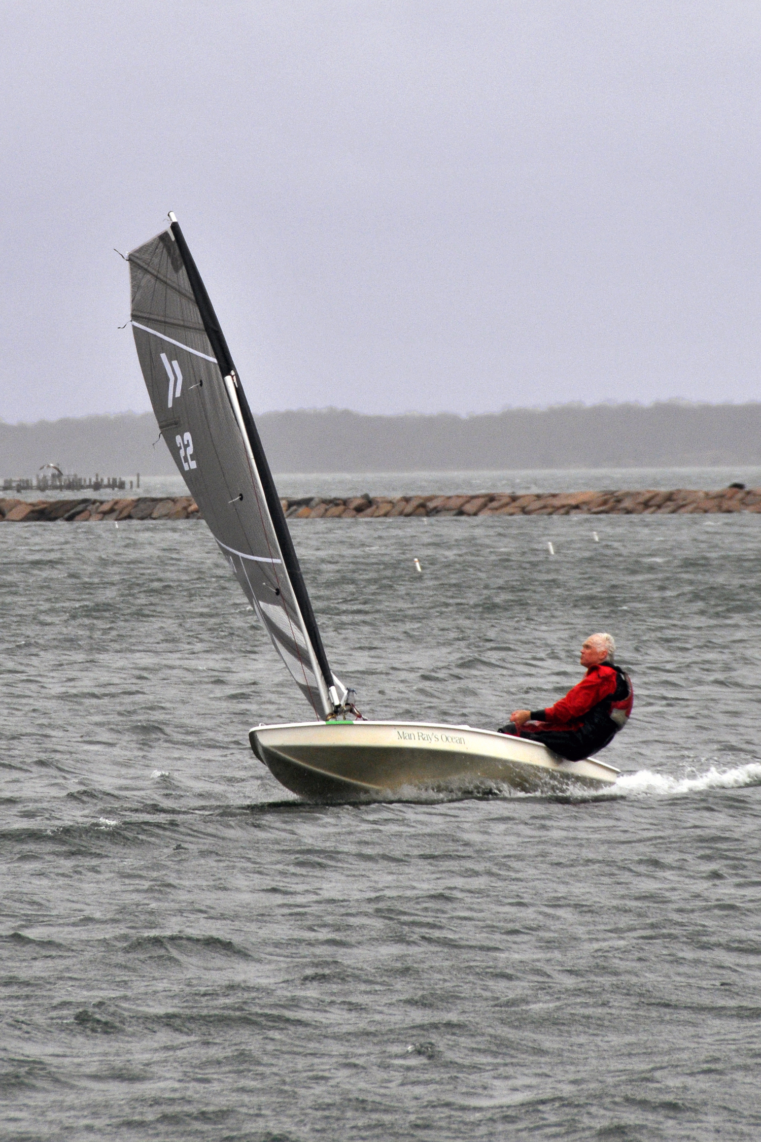 Scott Sandell felt an ardent desire to demonstrate his new black carbon fiber sail to fellow club members, and he did just that. The chase boat covered his every tack and jibe as he careened solo around the inner harbor at breakneck, planning speeds.